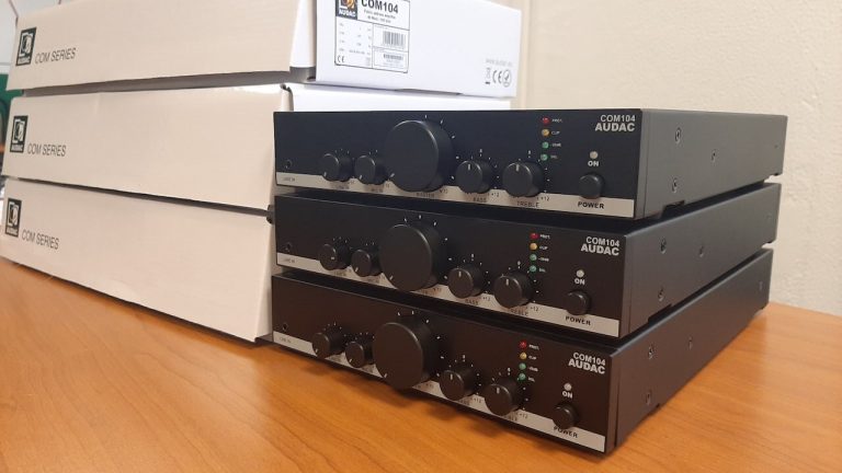 Trois amplificateurs mélangeurs AUDAC COM104 empilés devant leurs cartons, avant pose