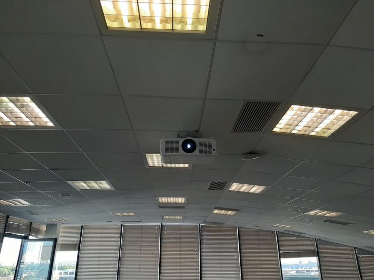 Vidéoprojecteur fixé au plafond à dalles d'une grande salle vitrée équipée de stores