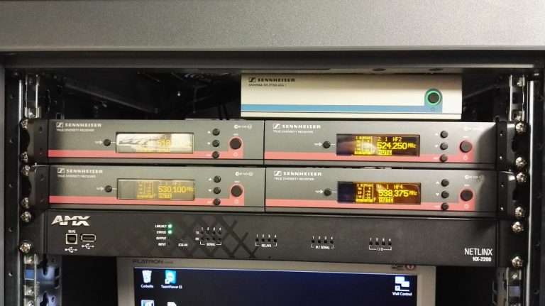 Baie technique avec quatre récepteurs de micros sans fil Sennheiser, un répartiteur d'antenne et un contrôleur AMX
