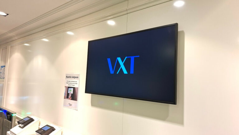 Gros plan sur un écran mural affichant le logo Samsung VXT, près d'une affiche d'information destinée aux collaborateurs